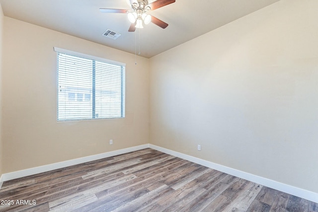 spare room with ceiling fan, wood finished floors, visible vents, and baseboards