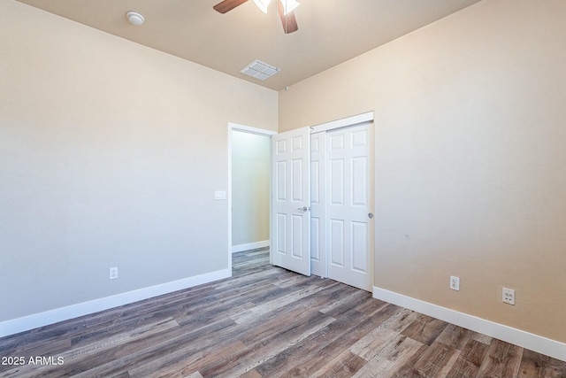 unfurnished bedroom with a closet, wood finished floors, visible vents, and baseboards