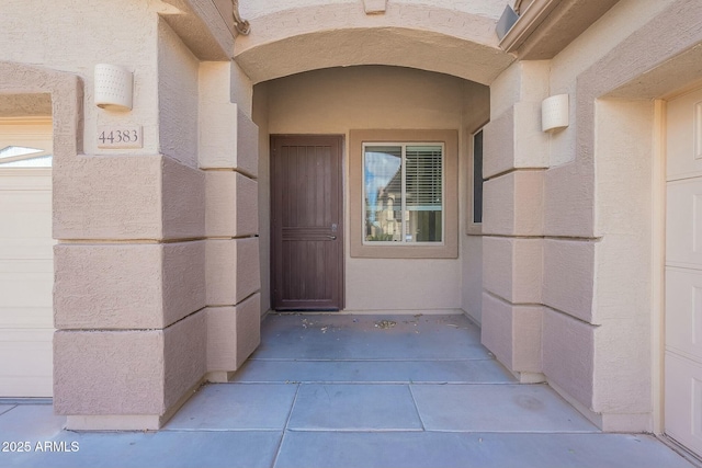 entrance to property with a garage and stucco siding