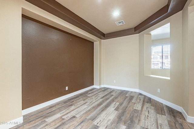 spare room featuring baseboards, visible vents, and wood finished floors