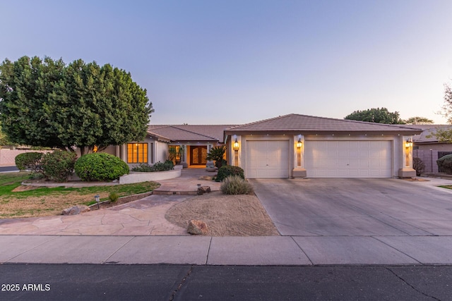 view of front facade featuring driveway, an attached garage, a tile roof, and stucco siding