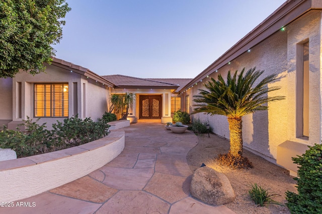 view of exterior entry featuring a patio area and stucco siding