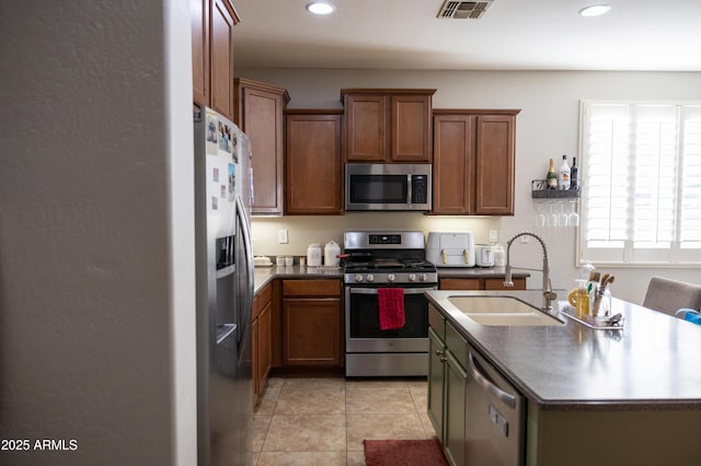 kitchen with dark countertops, visible vents, appliances with stainless steel finishes, and a sink