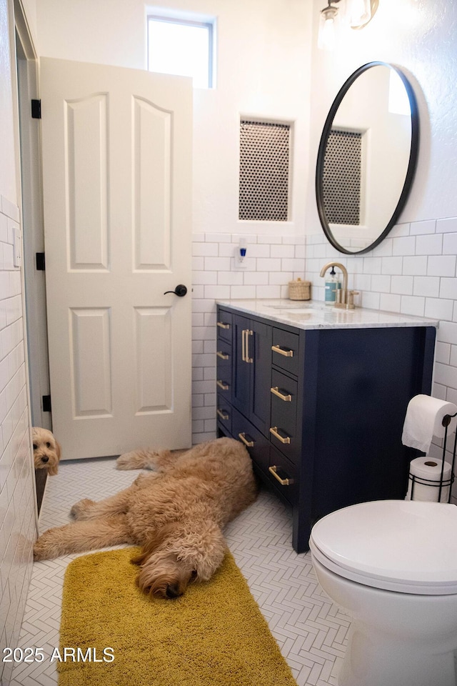 bathroom with tile patterned flooring, toilet, tile walls, and vanity