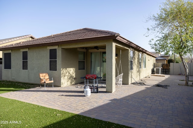 rear view of house featuring ceiling fan, a patio area, fence, and stucco siding