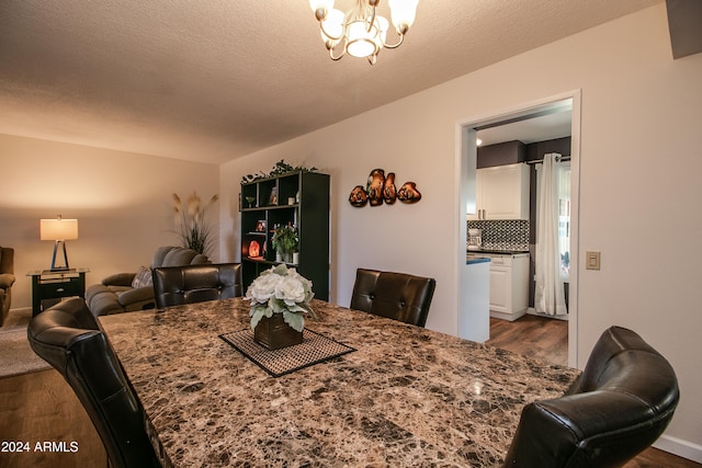 dining area featuring a textured ceiling, dark wood-type flooring, and a notable chandelier