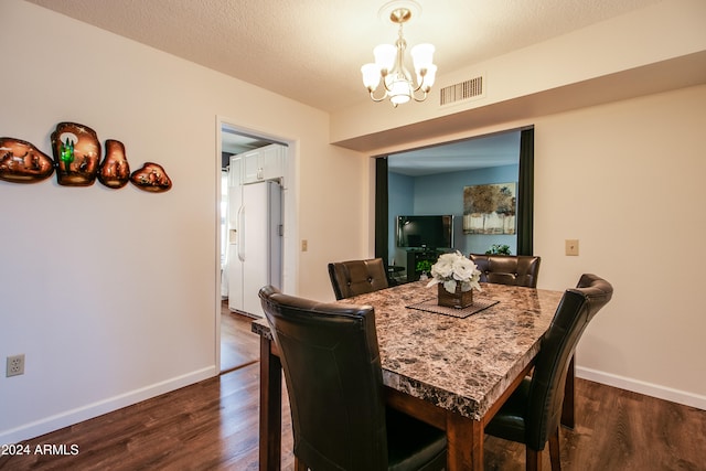 dining space with dark wood-type flooring, a textured ceiling, and a notable chandelier