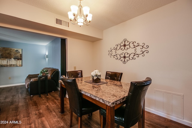 dining space with a chandelier, dark wood-type flooring, and a textured ceiling