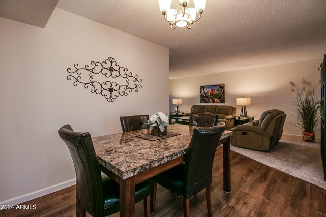 dining room featuring dark hardwood / wood-style flooring, a textured ceiling, and an inviting chandelier