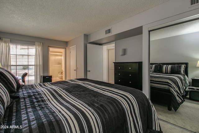 carpeted bedroom with connected bathroom and a textured ceiling