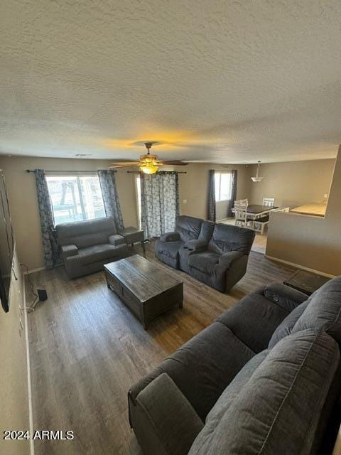 living room featuring a textured ceiling, hardwood / wood-style floors, and ceiling fan