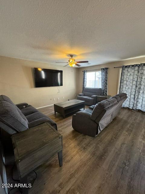 living room featuring a textured ceiling, hardwood / wood-style flooring, and ceiling fan