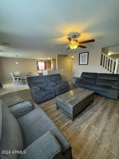 living room with a textured ceiling, hardwood / wood-style flooring, and ceiling fan