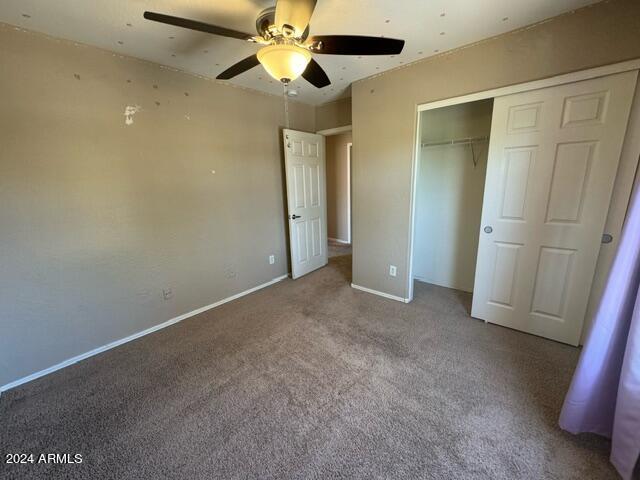 unfurnished bedroom with carpet, ceiling fan, and a closet