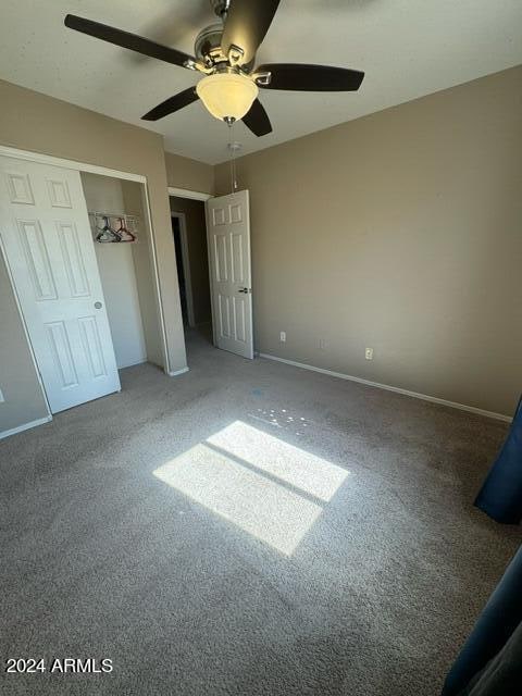 unfurnished bedroom featuring ceiling fan, a closet, and carpet