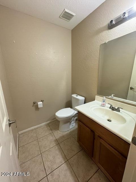 bathroom with vanity, toilet, a textured ceiling, and tile patterned floors