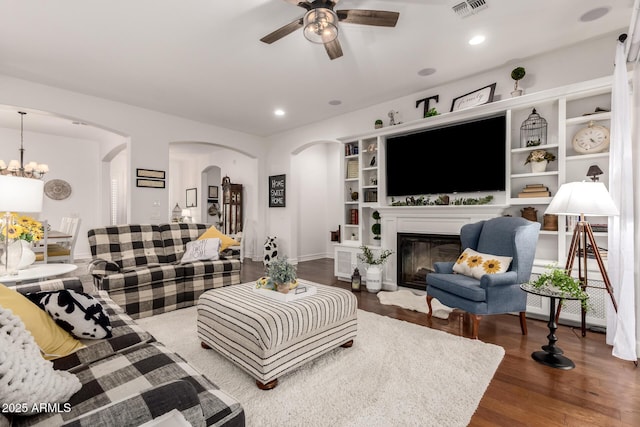 2879 E Austin Dr, Gilbert, AZ 85296 - living room featuring arched walkways, a ceiling fan, dark wood finished floors, a glass covered fireplace, and built in features