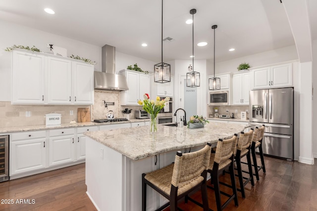 2879 E Austin Dr, Gilbert, AZ 85296 - kitchen with appliances with stainless steel finishes, wall chimney range hood, a sink, dark wood-type flooring, and backsplash