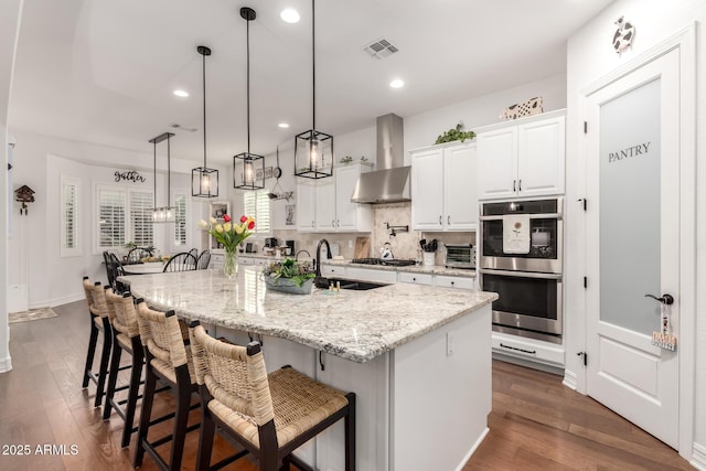 2879 E Austin Dr, Gilbert, AZ 85296 - kitchen with stainless steel appliances, wall chimney exhaust hood, a sink, dark wood-style floors, and white cabinets