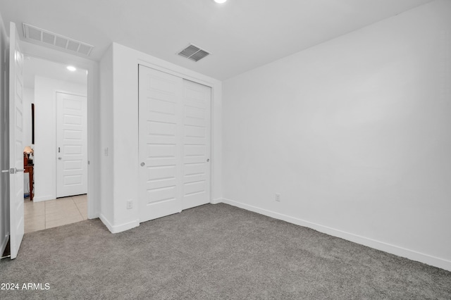 unfurnished bedroom with light colored carpet and a closet