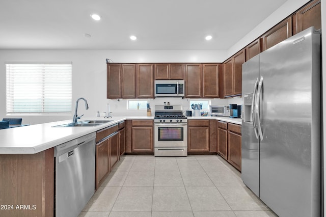 kitchen with kitchen peninsula, sink, light tile patterned floors, and stainless steel appliances