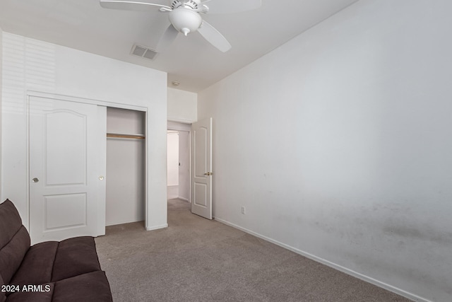 unfurnished bedroom featuring light colored carpet, a closet, and ceiling fan