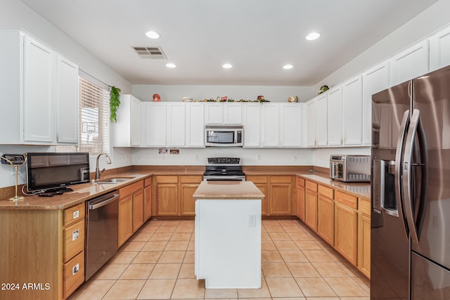 kitchen featuring sink, light tile patterned flooring, appliances with stainless steel finishes, and a center island