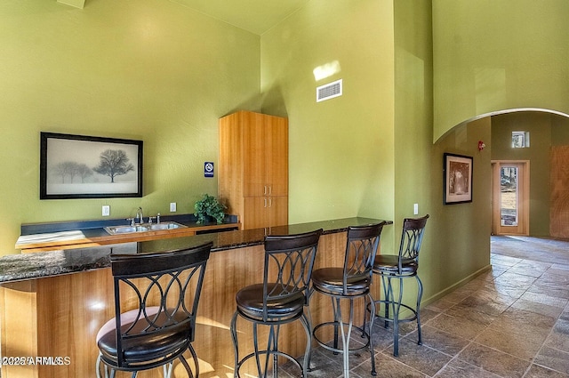 1185 W University Ave Unit 228, Flagstaff, AZ 86001 - indoor wet bar with arched walkways, a towering ceiling, and stone tile flooring
