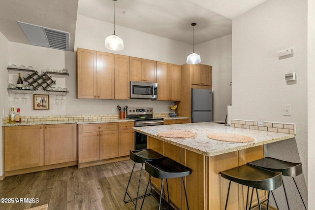 1185 W University Ave Unit 228, Flagstaff, AZ 86001 - kitchen with stainless steel appliances, a peninsula, a kitchen breakfast bar, dark wood-type flooring, and pendant lighting