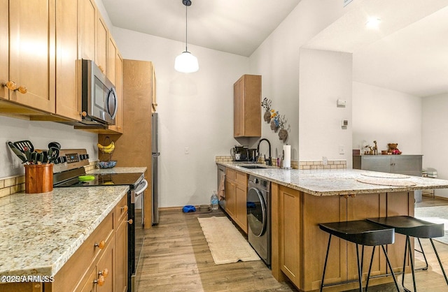 1185 W University Ave Unit 228, Flagstaff, AZ 86001 - kitchen with stainless steel appliances, a peninsula, light wood-type flooring, a kitchen breakfast bar, and washer / dryer