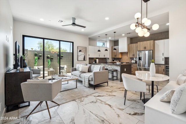 living room featuring ceiling fan with notable chandelier and sink