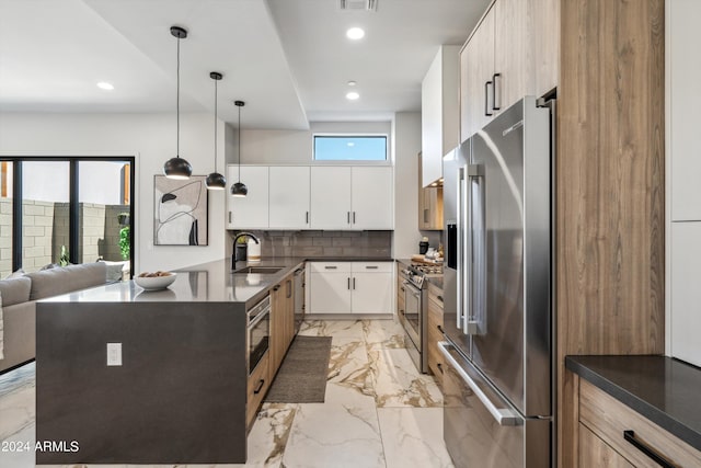 kitchen with sink, decorative light fixtures, white cabinets, stainless steel appliances, and backsplash