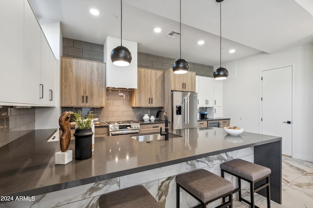 kitchen featuring sink, white cabinetry, hanging light fixtures, appliances with stainless steel finishes, and decorative backsplash