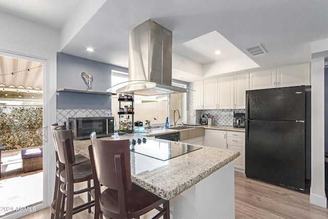 kitchen with white cabinets, island range hood, sink, and black appliances