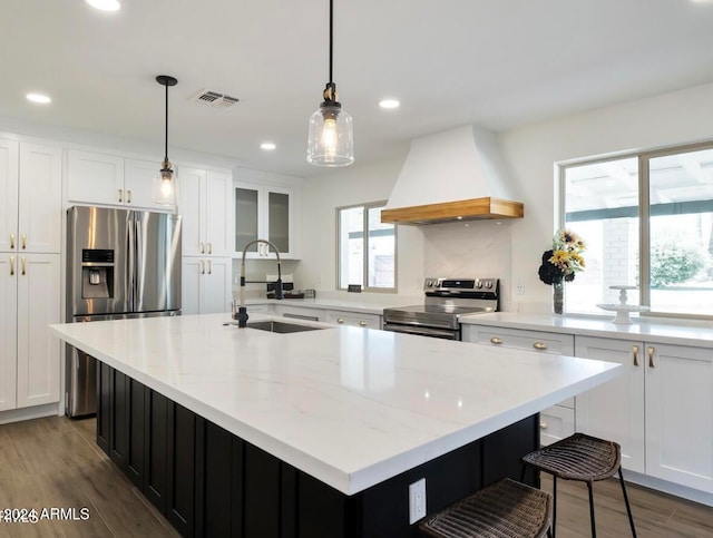 kitchen with sink, stainless steel appliances, a center island with sink, and custom exhaust hood