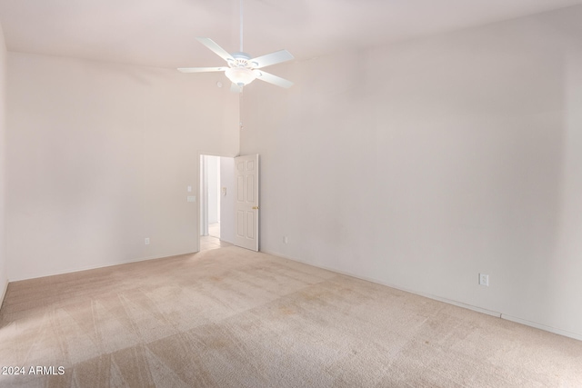 unfurnished room with a high ceiling, light colored carpet, and ceiling fan