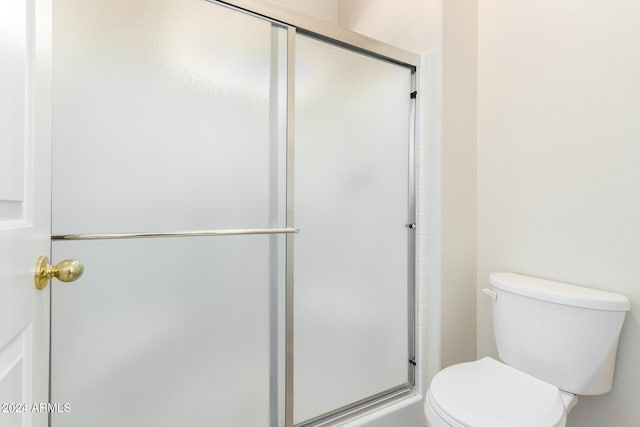 bathroom with a shower with door and toilet