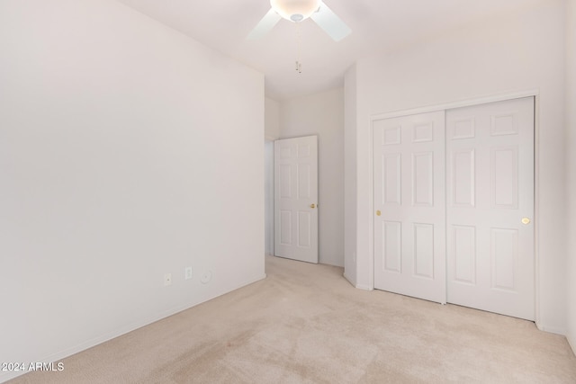 unfurnished bedroom with a closet, a skylight, light colored carpet, and ceiling fan