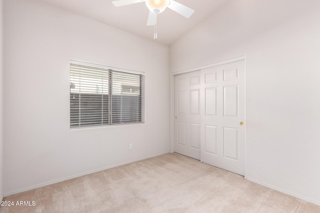 unfurnished bedroom with ceiling fan, a closet, vaulted ceiling, and light colored carpet