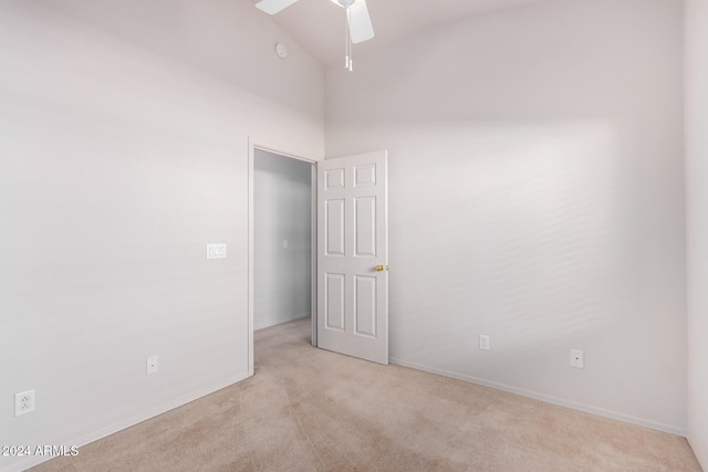 carpeted empty room with high vaulted ceiling and ceiling fan