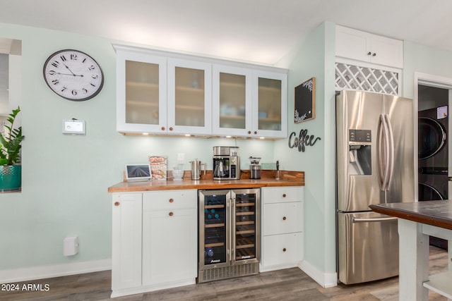 bar featuring butcher block countertops, stainless steel fridge with ice dispenser, stacked washer and dryer, and wine cooler