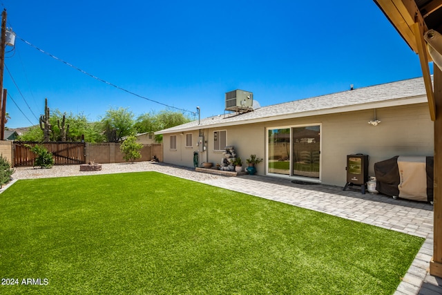 back of property with a lawn, central AC, a patio, and an outdoor fire pit