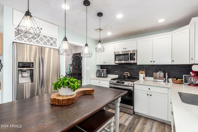 kitchen with white cabinetry, stainless steel appliances, and hanging light fixtures