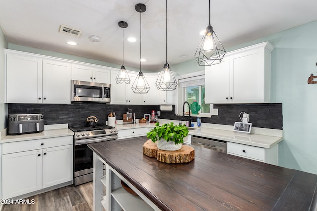 kitchen featuring white cabinets, decorative light fixtures, backsplash, and stainless steel appliances