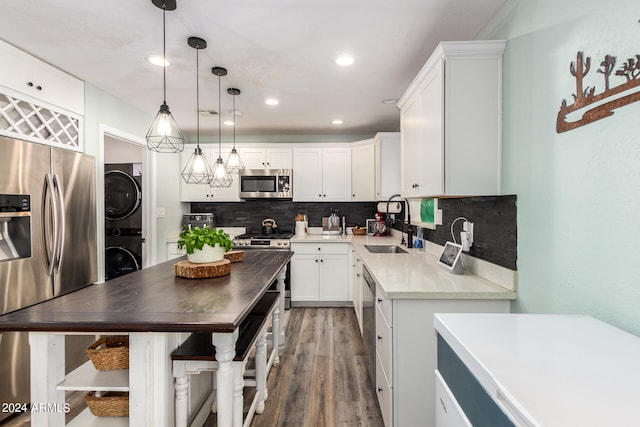 kitchen featuring white cabinets, stacked washer and dryer, hanging light fixtures, dark hardwood / wood-style flooring, and stainless steel appliances