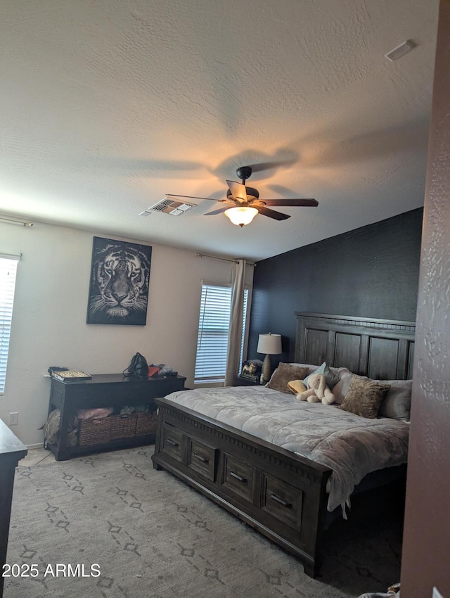 carpeted bedroom featuring ceiling fan and a textured ceiling