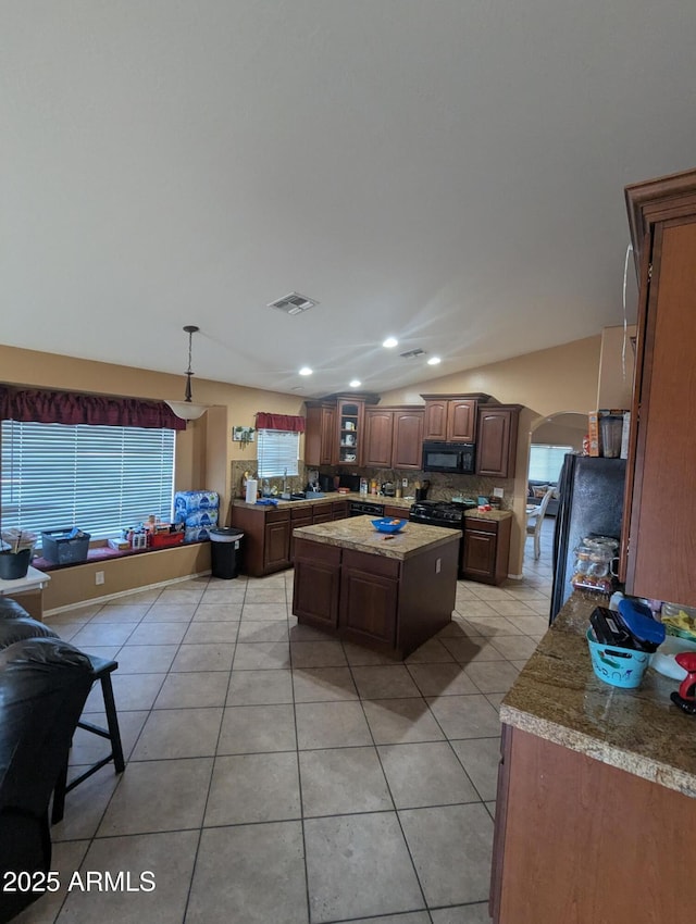 kitchen featuring vaulted ceiling, a kitchen island, backsplash, light tile patterned floors, and black appliances