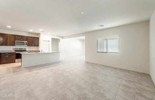 kitchen with visible vents, open floor plan, a kitchen island with sink, stainless steel appliances, and recessed lighting