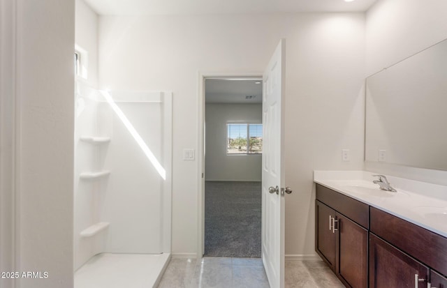 bathroom featuring tile patterned flooring, walk in shower, a sink, and double vanity