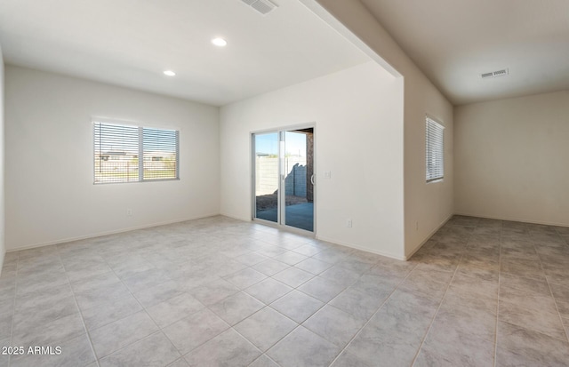 empty room with recessed lighting, a healthy amount of sunlight, visible vents, and baseboards